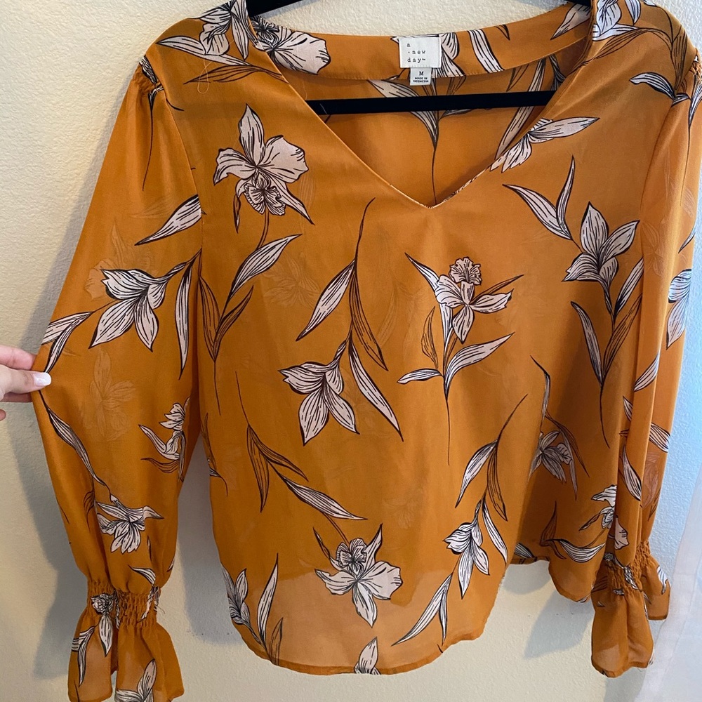 Orange long sleeved blouse with floral detailing